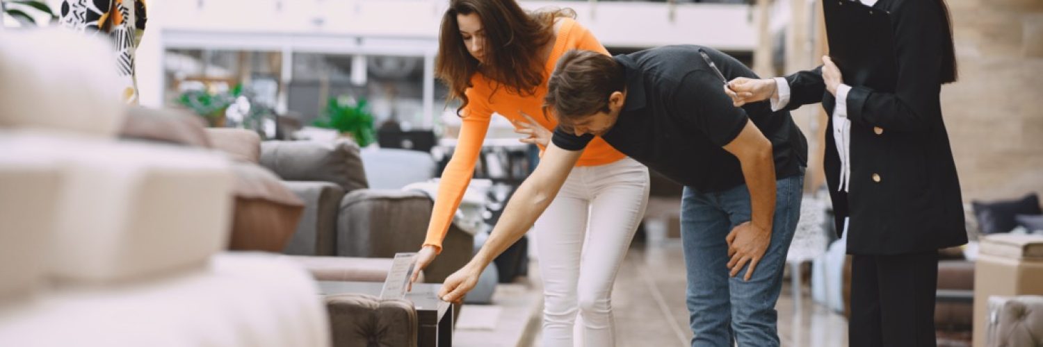 Couple in furniture store. Family choosing furniture in store while sales clerk consulting them.